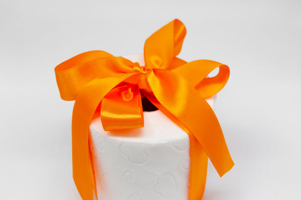 白色卫生纸卷，用鲜橙色缎带系成礼物图片下载