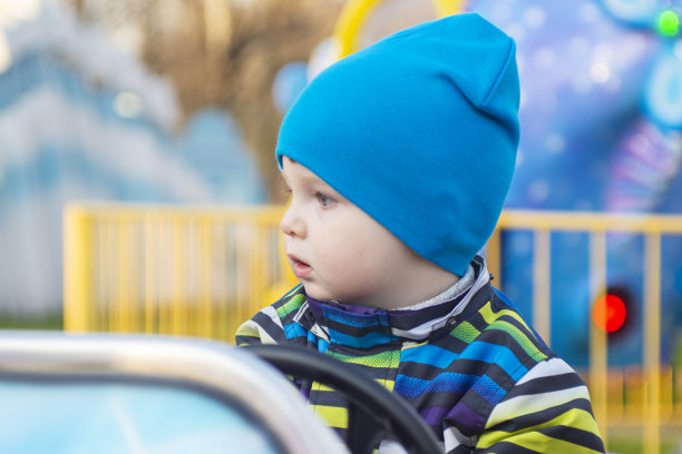 一个小婴儿在游乐园里开车。一个小司机。这个孩子正在开一辆玩具车。儿童游乐场。图片下载
