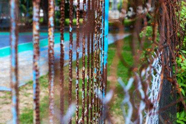 乡村网栅栏和大门概念照片。金属网带褐色锈迹。老花园篱笆。金属丝栅栏生锈。夏季运动庭院后的网围栏。废弃旅馆里空荡荡的网球场图片下载