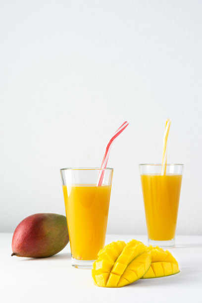 用玻璃杯装的芒果汁和一根吸管图片下载