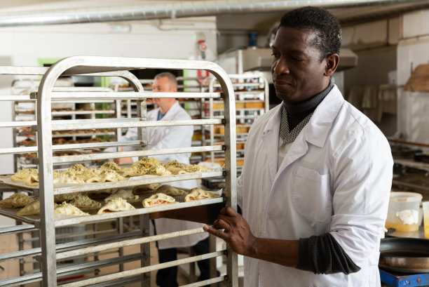 面包店老板把新鲜的烘培食品放在手推车上图片下载