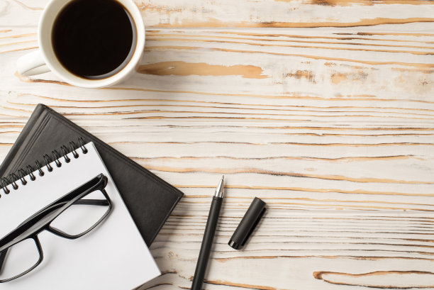 上面的照片是放在木桌上的笔记本、咖啡杯、文件夹和钢笔图片下载