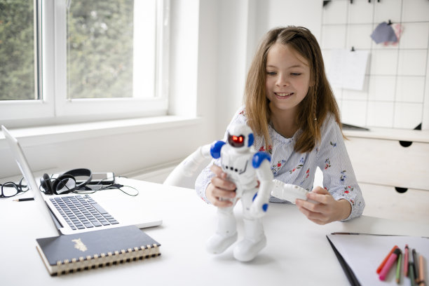 年轻的金发女学生正在玩她的机器人玩具图片下载