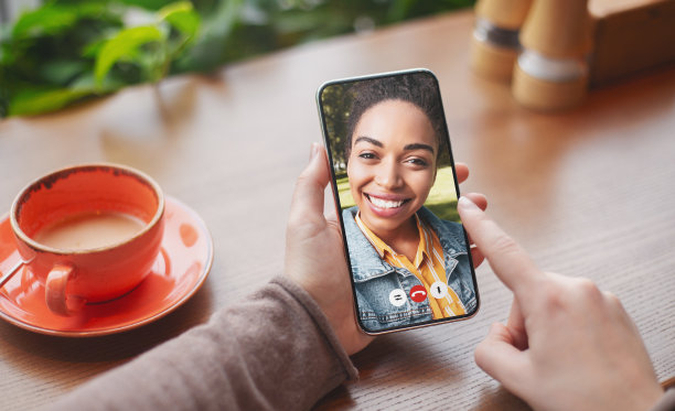一个年轻的女人和她的非洲裔美国朋友在咖啡馆的手机聊天图片下载