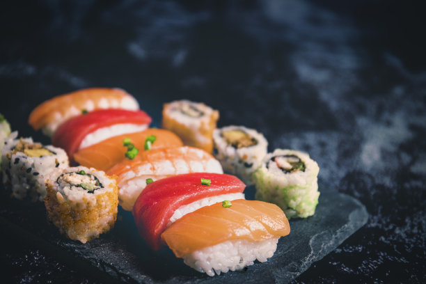 寿司设置在黑色的石头石板上，在黑色的背景上选择性聚焦复制空间图片下载