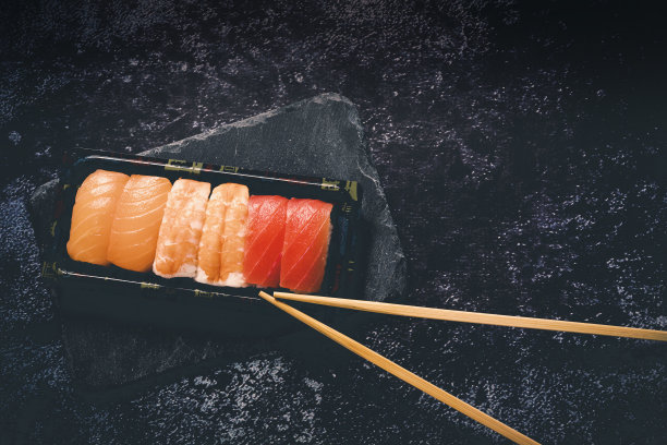 寿司设置在黑色的石头石板上，在黑色的背景上选择性聚焦复制空间图片下载
