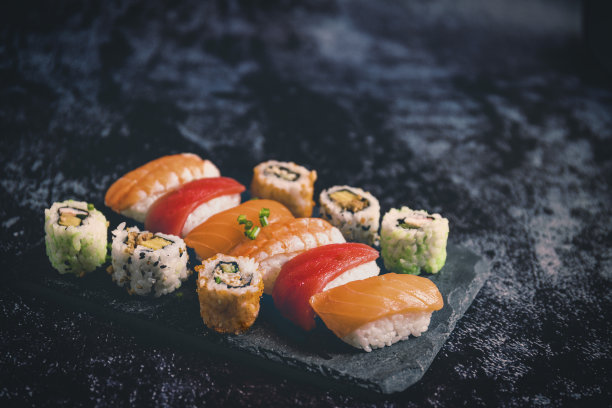 寿司设置在黑色的石头石板上，在黑色的背景上选择性聚焦复制空间图片下载