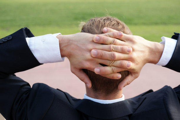 商人放松地坐在城市公园的长椅上，双手放在脑后图片下载