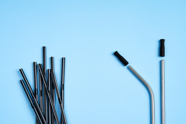关心环境的现代趋势。一包黑色塑料饮料吸管，而只有两根可重复使用的金属饮料吸管，带硅胶盖图片下载