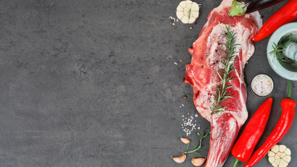 生羊全腿、羊肩肉，配以香料、佐料和药草的概念烹饪菜肴。俯视图，鲜肉在深色的石头桌上，产品布局与食谱复制空间图片下载