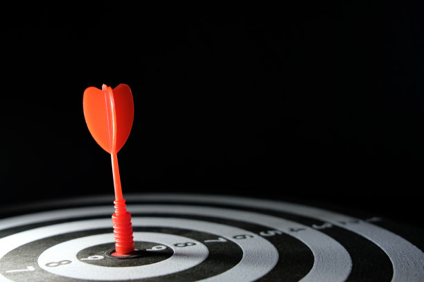 商业策略/精确度的概念性照片——一个红色的箭头，直接钉在靶靶的中心。图片下载