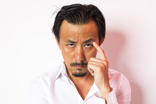中年亚洲男子的头，严肃地看着白色的背景。图片下载