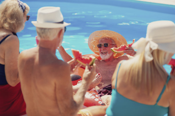年长的朋友在游泳池里吃西瓜片图片下载