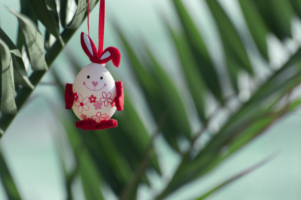 沙滩上的棕榈树枝头挂着带着兔子耳朵和快乐笑脸的复活节装饰彩蛋。复活节假期旅游或海滨度假度假概念。背景,复制空间图片下载