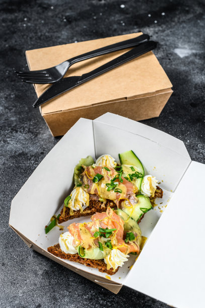 送早餐的纸盒，还有三明治。黑色背景。俯视图图片下载