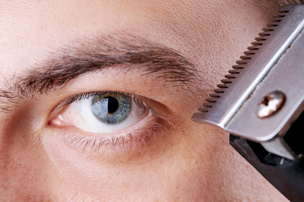 一个白人男性梳理眉毛的特写照片。宏。影棚拍摄。中期的年龄。蓝色的眼睛图片下载