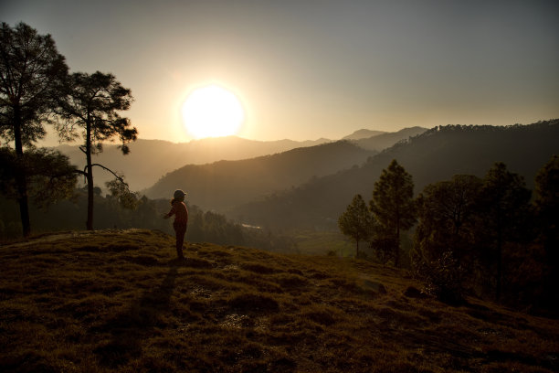 女孩在日落时欣赏风景优美的山景图片下载