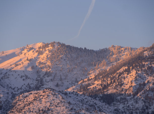 在希腊埃维亚岛(Euboea)的云层背景下，迪菲斯山云杉森林在日落时积雪覆盖的山峰全景图片下载