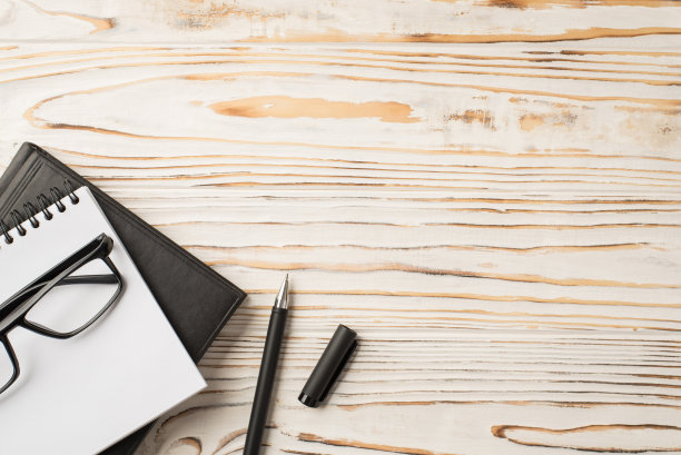 上面的照片是放在木桌上的笔记本文件夹和钢笔图片下载