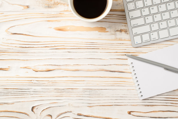 照片上方的键盘、记事本、钢笔和咖啡杯放在木桌上图片下载
