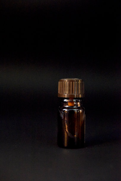 黑色背景上的小棕色玻璃瓶。低光,工作室。炼金术和医学概念图片下载