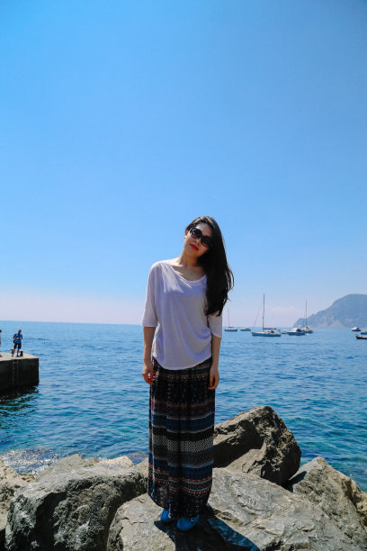 一位女游客站在海边的岩石上，Vernazza, Cinque Terre地区，意大利图片下载