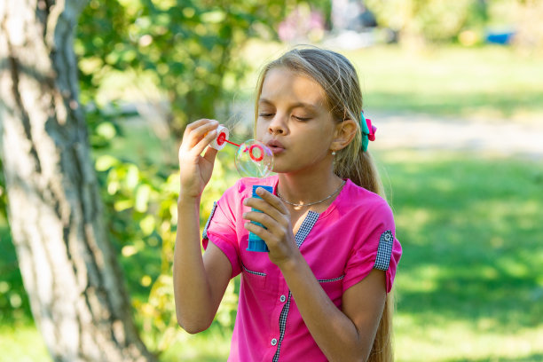 在一个阳光明媚的日子里，女孩在公园里吹肥皂泡图片下载
