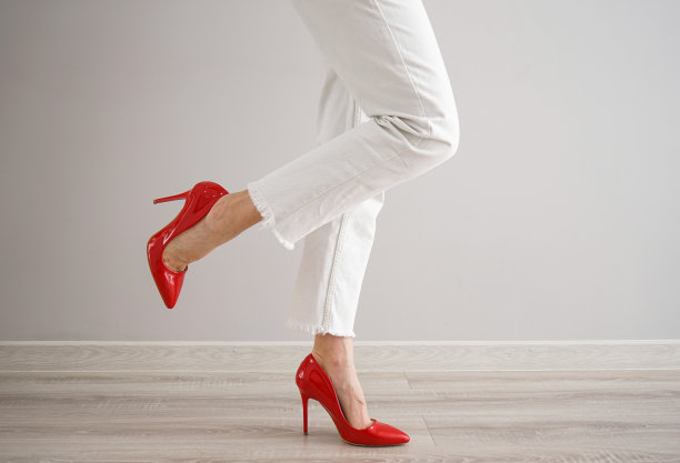 一个穿着白色牛仔裤和红色鞋子，灰色背景的年轻女孩的腿。图片下载