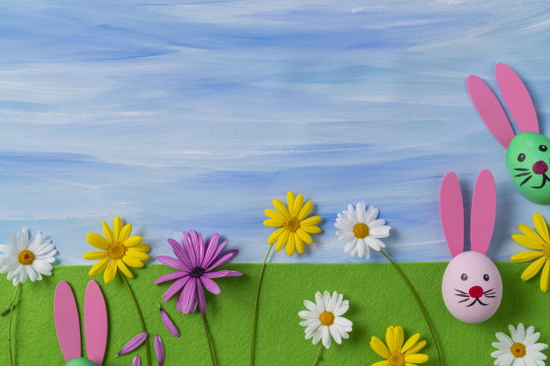 在绿色的毛毡上画有复活节兔子的脸和水彩蓝色的天空图片下载