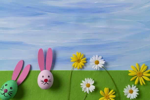 在绿色的毛毡上画有复活节兔子的脸和水彩蓝色的天空图片下载
