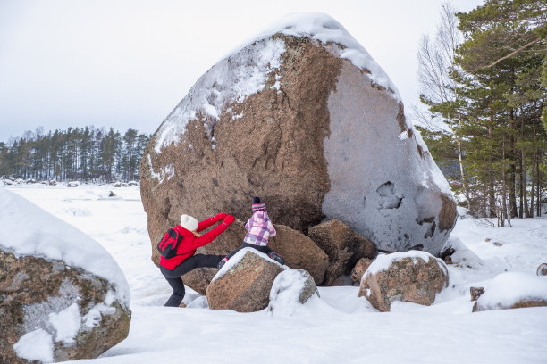 一个白人家庭，母亲和女儿，正在海边玩，在一个巨大的花岗岩石头玩。冬季家庭周末在城外图片下载