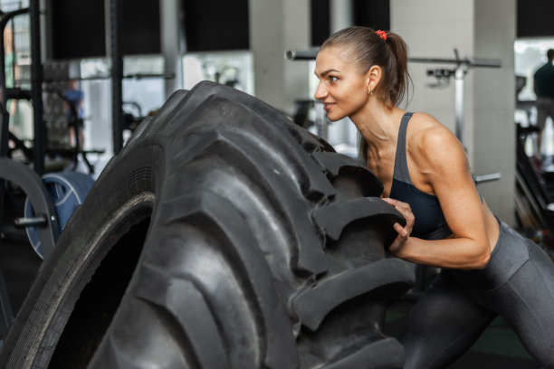 年轻的健身女在现代健身房里推着大轮子。功能训练。健康的生活方式图片下载