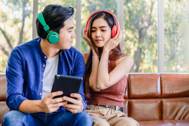 快乐的亚洲年轻夫妇坐在放松和听音乐从耳机图片下载