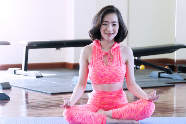 美丽的年轻女子穿着橙色运动服瑜伽健身背景。运动的概念。图片下载