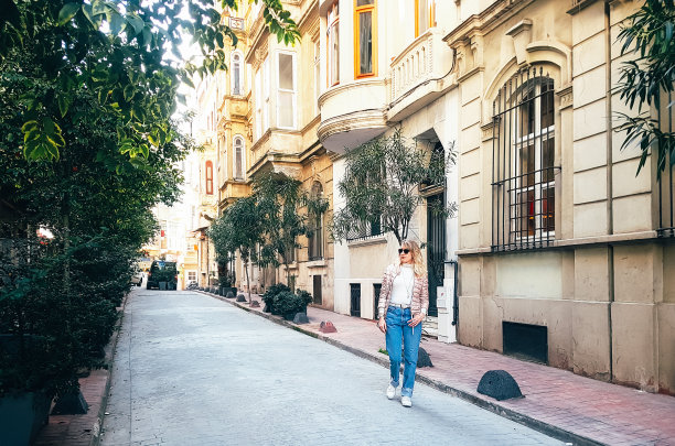 金发女人走在一个大城市的老街上图片下载