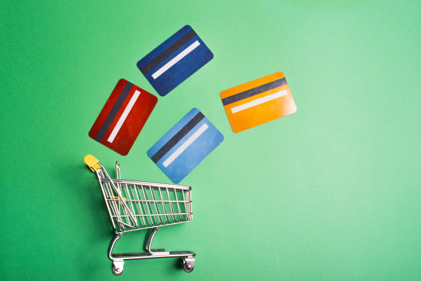 俯视图照片购物手推车在绿色背景与彩色信用卡图片下载