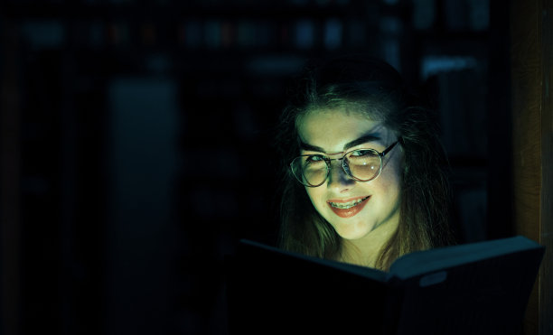 神秘的绿光来自于这本书。创造力的概念。女学生在图书馆。教育的概念图片下载