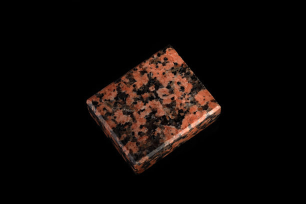 一个天然石的标本的特写红色花岗岩矿物石上的黑色玻璃。一块抛光的红色花岗岩矿物。图片下载