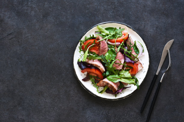 将沙拉、西红柿和中号牛肉放在一个盘子里，背景颜色要深一些。图片下载