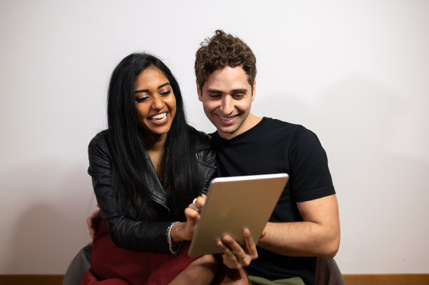 愉快的多民族夫妇放松在家里浏览平板电脑图片下载