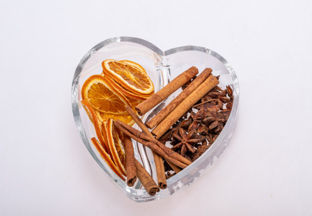几片干橙子、肉桂和小豆蔻放在一个心形的玻璃盘子里图片下载
