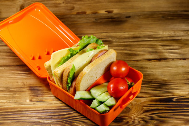 木桌上放着午餐盒，里面有三明治和新鲜蔬菜图片下载