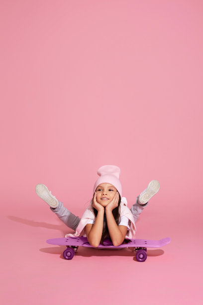 小女孩笑着坐在粉红色的滑板上图片下载
