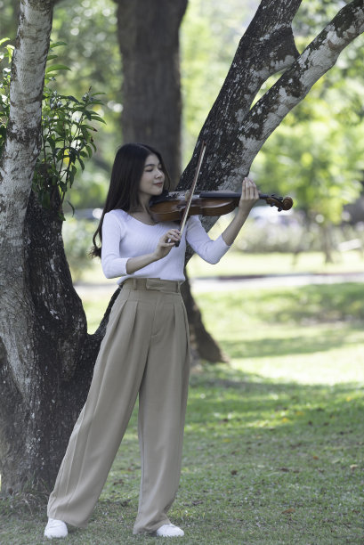 美丽的女子捧着小提琴，在自然风景的背景下，在情感上感受着幸福。图片下载