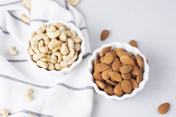 天然有机烤未剥皮杏仁，腰果在一个轻的背景。脂肪和油脂的标准，生酮饮食和健康小吃的基础。坚果油是维生素的来源。图片下载