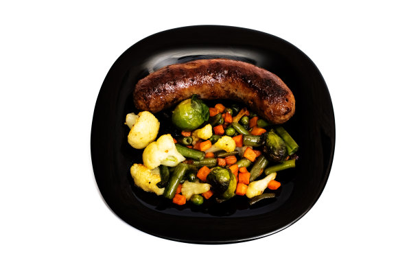 烤蔬菜和香肠放在一个黑色盘子孤立图片下载