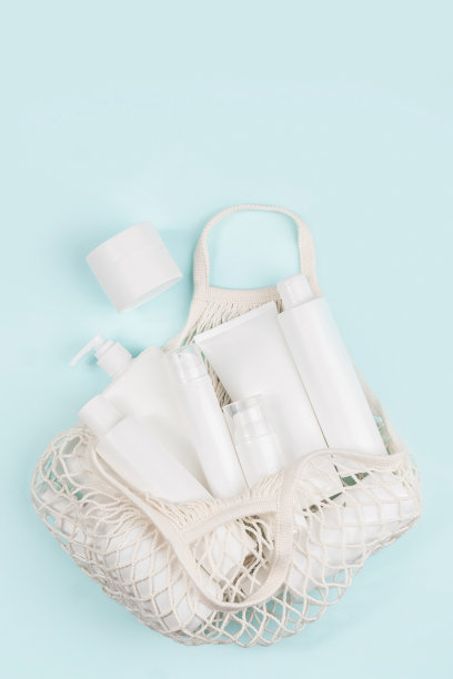 一套护肤面部、身体、头发的化妆品。白色空白化妆品瓶，管，瓶在环保购物袋在蓝色背景。天然有机Spa美容概念图片下载