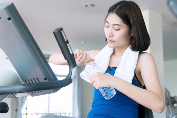 迷人的年轻女子拿着一个水瓶在健身。苗条女性在健身房锻炼健康的生活方式图片下载