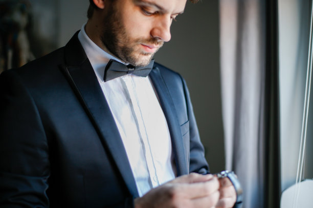 英俊的年轻人看着他的手表。库存图片图片下载