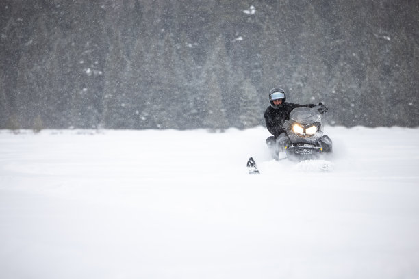 一名男子开着雪地摩托在粉状积雪中超速行驶图片下载